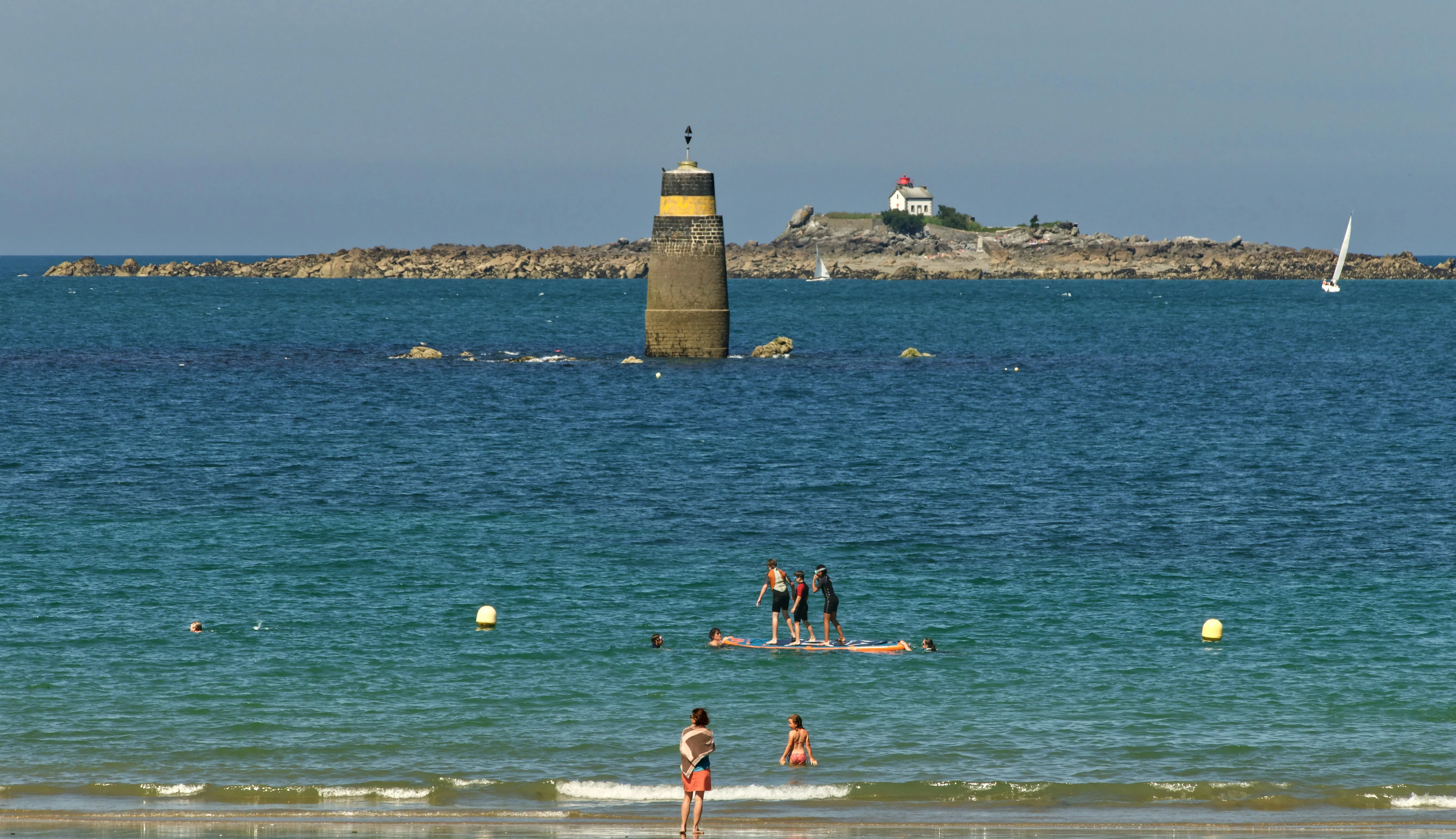 Une plage bretonne où des personnes se baignent et font du stand up paddle